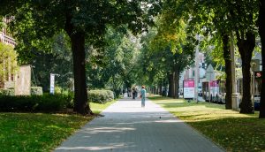 Cilvēki iet pa ielu, kamēr skolēni Rīgas centrā piedalās projektā “Elpo, Rīga!”, nēsājot sensorus gaisa kvalitātes mērīšanai
