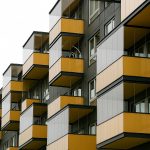 Infografika par nekustamā īpašuma nodokļa piemērošanas aktualitātēm Rīgā 2026. gadā, samazinātām likmēm, deklarēšanas nosacījumiem un atvieglojumu saņemšanas kārtību.