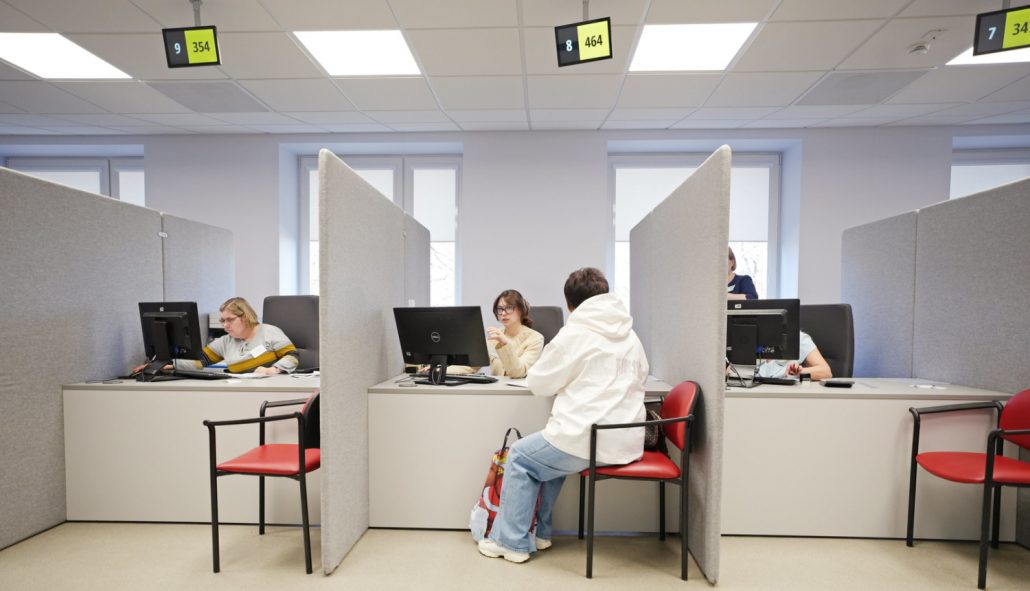 Mājokļa pabalsts Rīga īre – dzīvojamā ēka pilsētvidē ar iedzīvotājiem, ilustrējot pašvaldības sniegto finansiālo atbalstu mājsaimniecībām, kuras saskaras ar grūtībām segt īres maksas izmaksas Rīgā.