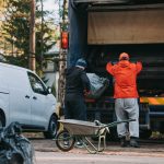 Iedzīvotāji pie specializētā atkritumu savākšanas transportlīdzekļa izkrauj savāktās rudens lapas. Attēlā redzami lapu maisi, ķerra un lapu savākšanas darbi. Attēls ilustrē rudens lapu pieņemšanas punktus Rīgā un lapu nodošanas procesu.